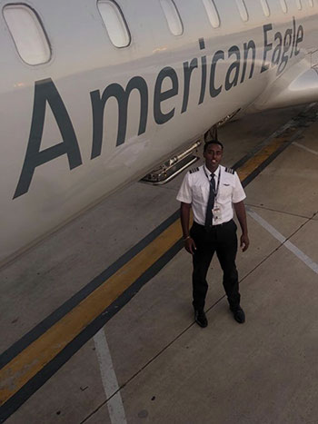 Ashenafi Tadese standing next to an American Eagle passenger plane