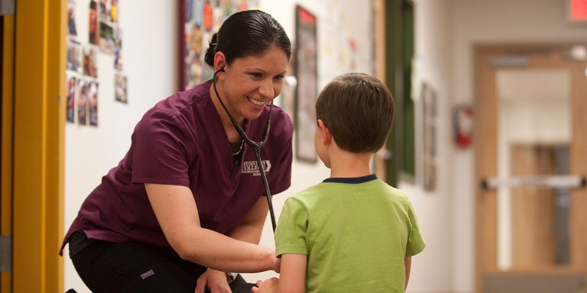 2016 Hesston College Nursing graduate Dra Aguilar (Wichita, Kan.) practices nursing skills on a young patient in this photo from 2015.