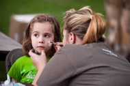 A young festival-goer gets her face painted by sophomore Danielle Hanna of Whitewater, Kan., at Friday night’s Tailgate Picnic and Family Festival.