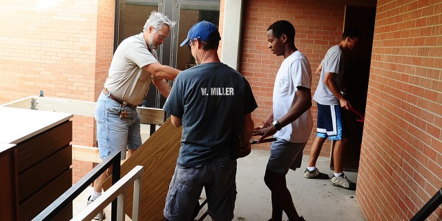 Hesston College Facilities staff Tim Goering and Forrest Miller and student Curtis Denlinger of Perkasie, Pa. move dressers from Erb Hall central and west.