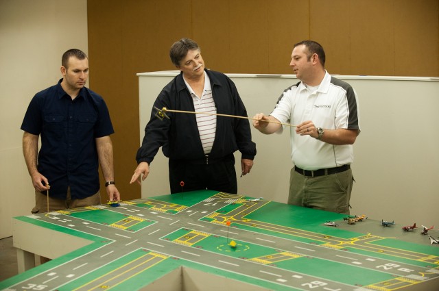Jerry Holloman (left) and Jacob Gayer (right), members of Hesston College's first class of Air Traffic Control graduates in May 2011, work with Director of Aviation Dan Miller in the on-campus table model simulation lab.