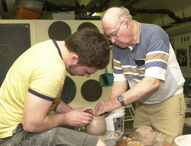 Paul Friesen, ceramics class professor at Hesston College, helps Jephry Henriksen, a freshman from Otter Rock, Ore., look at options for finishing a pot.