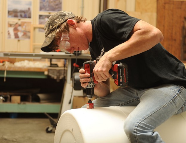 Freshman Matt Weaver (Goshen, Ind.) drills a spigot hole in a drum to be turned into a rain barrel.