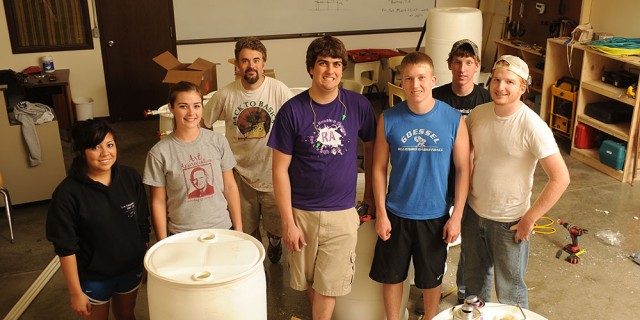 The Hesston College Entrepreneurship class takes a break from turning 55-gallon food-grade drums into rain barrels.