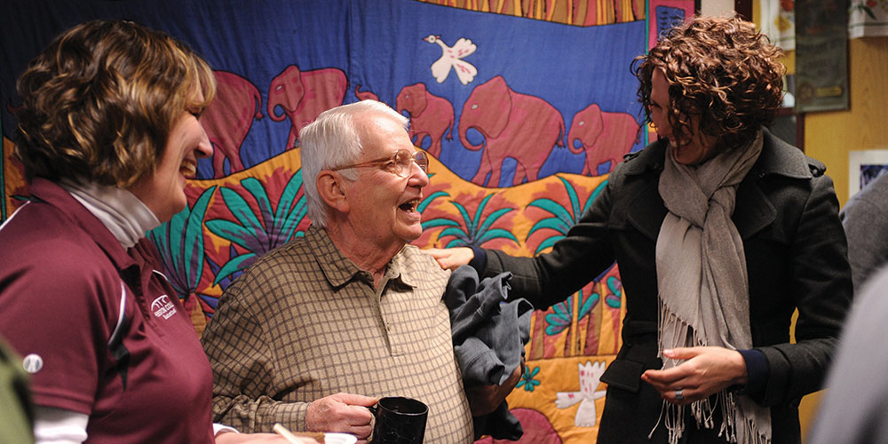 Bill Mason (center), longtime Hesston College employee, is congratulated by Melissa Unruh (left) and Rachel Swartzendruber Miller (right) during Mason’s retirement celebration at Hesston College Feb. 16.