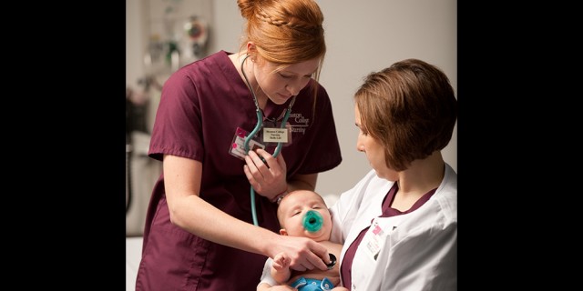 Hesston College nursing student Rachel Tippin (Newton, Kan.) listens to instructor Becky Bartell's son's heartbeat. 