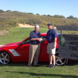 Tom West (left) shakes hands with Phil Nightingale, general manager of Mel Hambleton Ford, as he receives his hole-in-one prize of a 2013 Roush Stage 3 Ford Mustang at the Hesston College Kansas Golf Benefit at Prairie Dunes Country Club in Hutchinson.