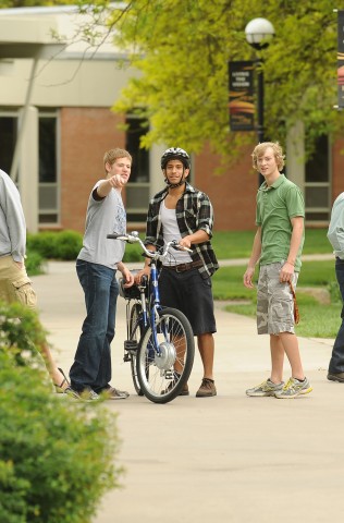 Adrian Rosas (Goshen, Ind.), a member of the Hesston College class of 2012, prepares to ride the electric bicycle with some instructions from classmates Kenny Graber (Stryker, Ohio) and Brad Sandlin (Valley Center, Kan.) during Hesston College's 2012 Earth Day celebration.