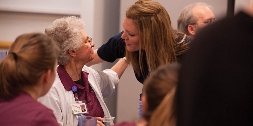 Nursing instructor Joyce Huber hugs a nursing alumna at a retirement break in Huber's honor.