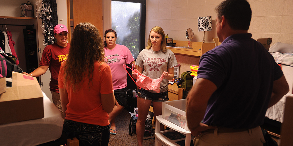 Hesston College freshmen Skylar Tripp and Kambree Carter and their parents talk with their resident assistant, Hayley Goevert, Hesston, Kan., as they move into the dorms Aug. 12.