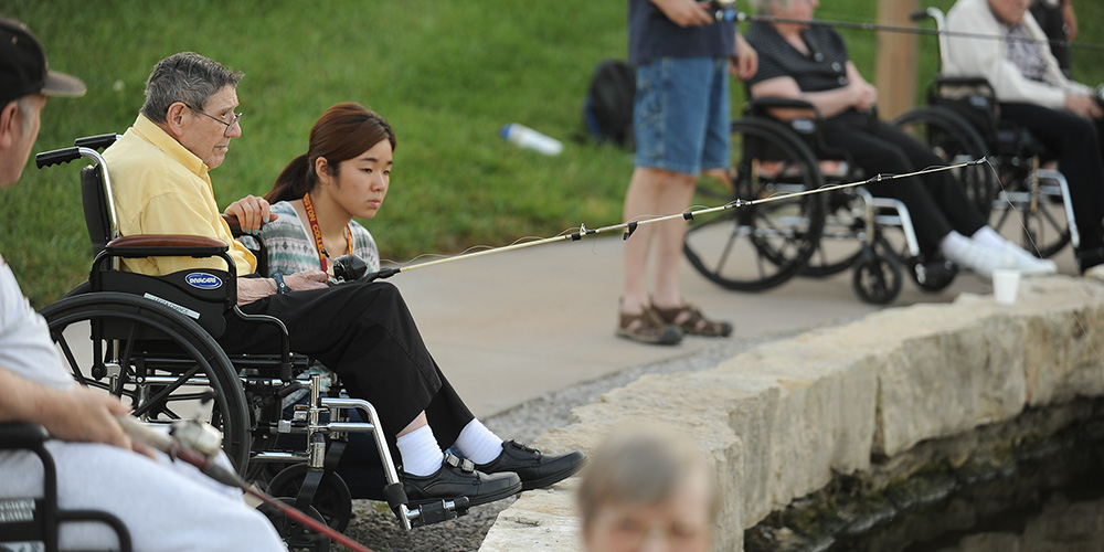 Misaki Murakami ’15 (Osaka, Japan) fishes with Schowalter Villa resident Allen Bitikofer Ac38 at Lake Vista as part of Service Week.