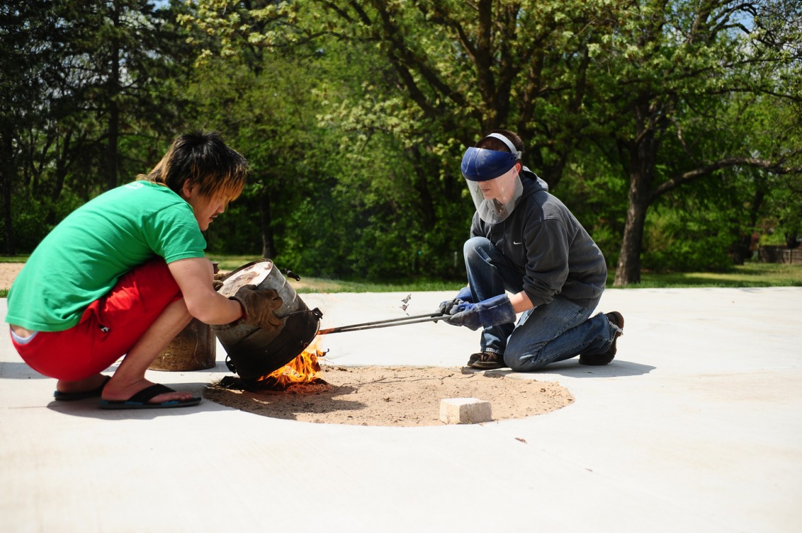 Hesston College ceramics instructor Hanna Eastin (right) and a student work on a raku firing of ceramics pieces.