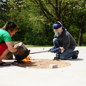 Hesston College ceramics instructor Hanna Eastin (right) and a student work on a raku firing of ceramics pieces.