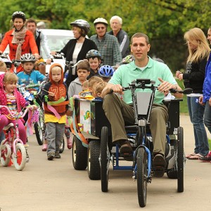 Mark Landes, Hesston College vice president of Finance and Auxiliary Services pulls a wagon of children from the college's preschool on a solar-charged personal activities vehicle to lead the Earth Day parade featuring alternative transportation options.