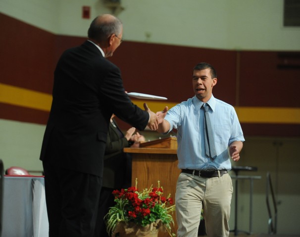 Simon Zehr receives his Hesston College diploma from President Howard Keim at during commencement exercises May 11. Zehr, who has Williams syndrome, overcame learning disability challenges to find success at Hesston College and graduate.
