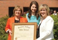 Three generations of Milo Kauffman's descendants hold his diploma at commencement.