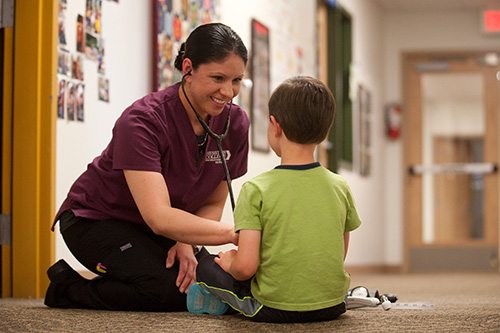 Dra Aguilar ’16 (Wichita, Kan.) listens to a child’s heartbeat at the Hesston Intergenerational Child Development Center.