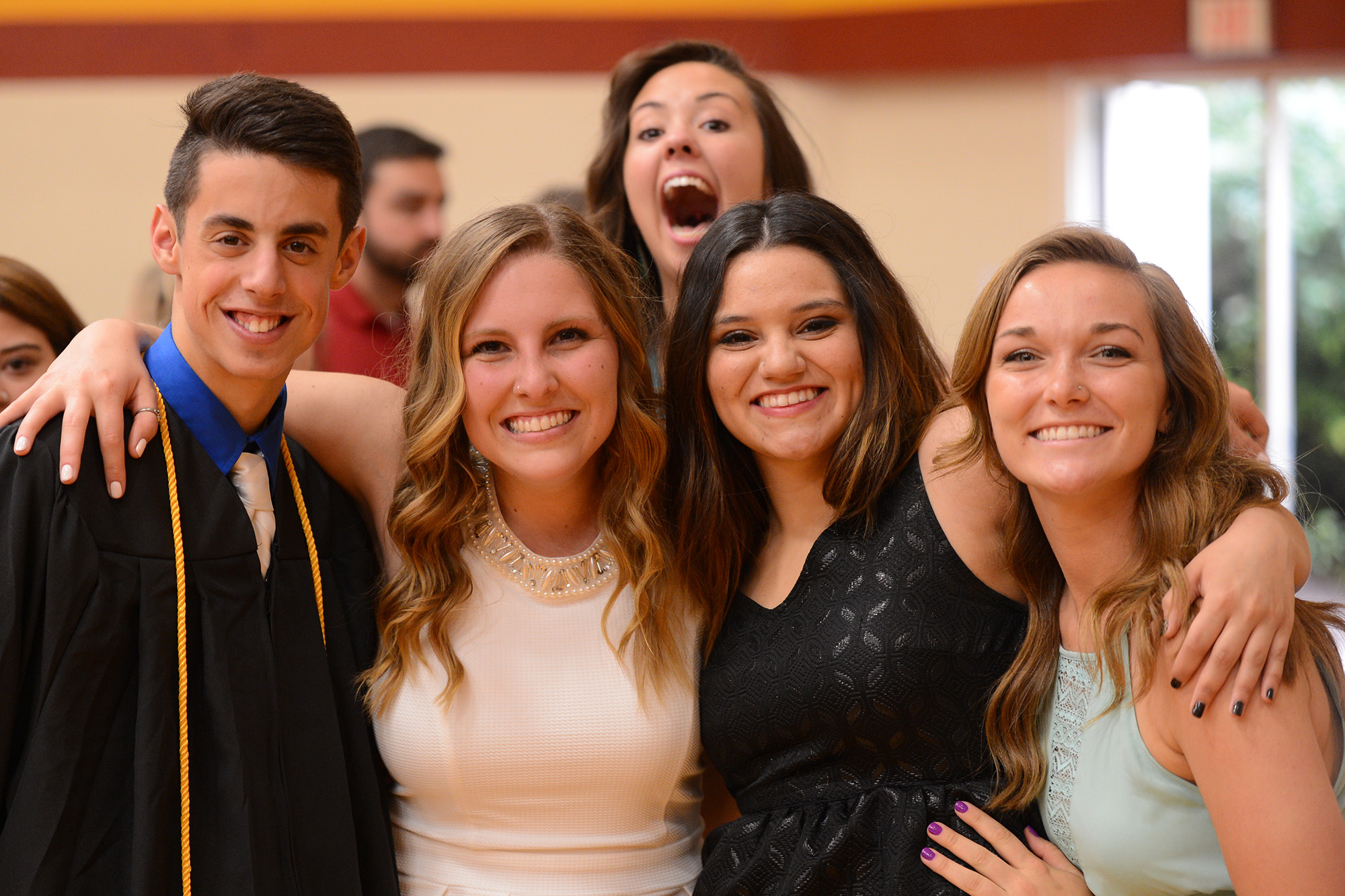 Graduates Bryce Nitzshe, Kiara Boettger, Casey Perez and Meredith Spicher take a final Hesston College photo together while Molly Bruner jumps in late.