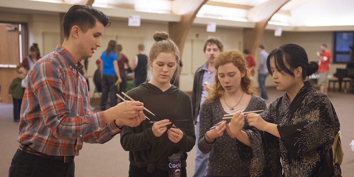 Hesston College sophomore Kaho Yanagidaira and English faculty member Donovan Tann give a lesson on using chopsticks to sophomores Morgan Leavy and Emily Griffioen at the college’s annual Culture’s Fair Oct. 10.