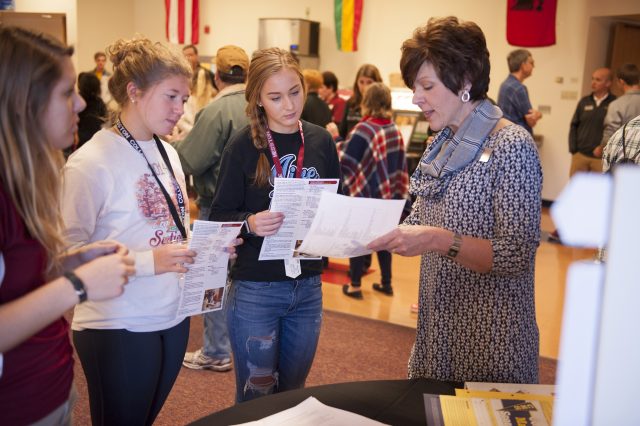 Deb Roth, Dean of Student Success (right), talks through a two-year plan of study with prospective students and admissions counselor Carley Wyse (left) during a Friday Experience Expo, highlighting academic and extracurricular opportunities at Hesston.