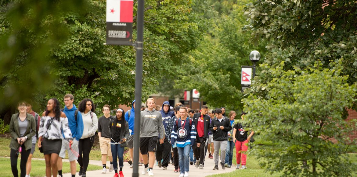 During Peace Day 2018, students walk the Hesston College Global Walkway, which is lined with flag representations of the countries Hesston College students call home.