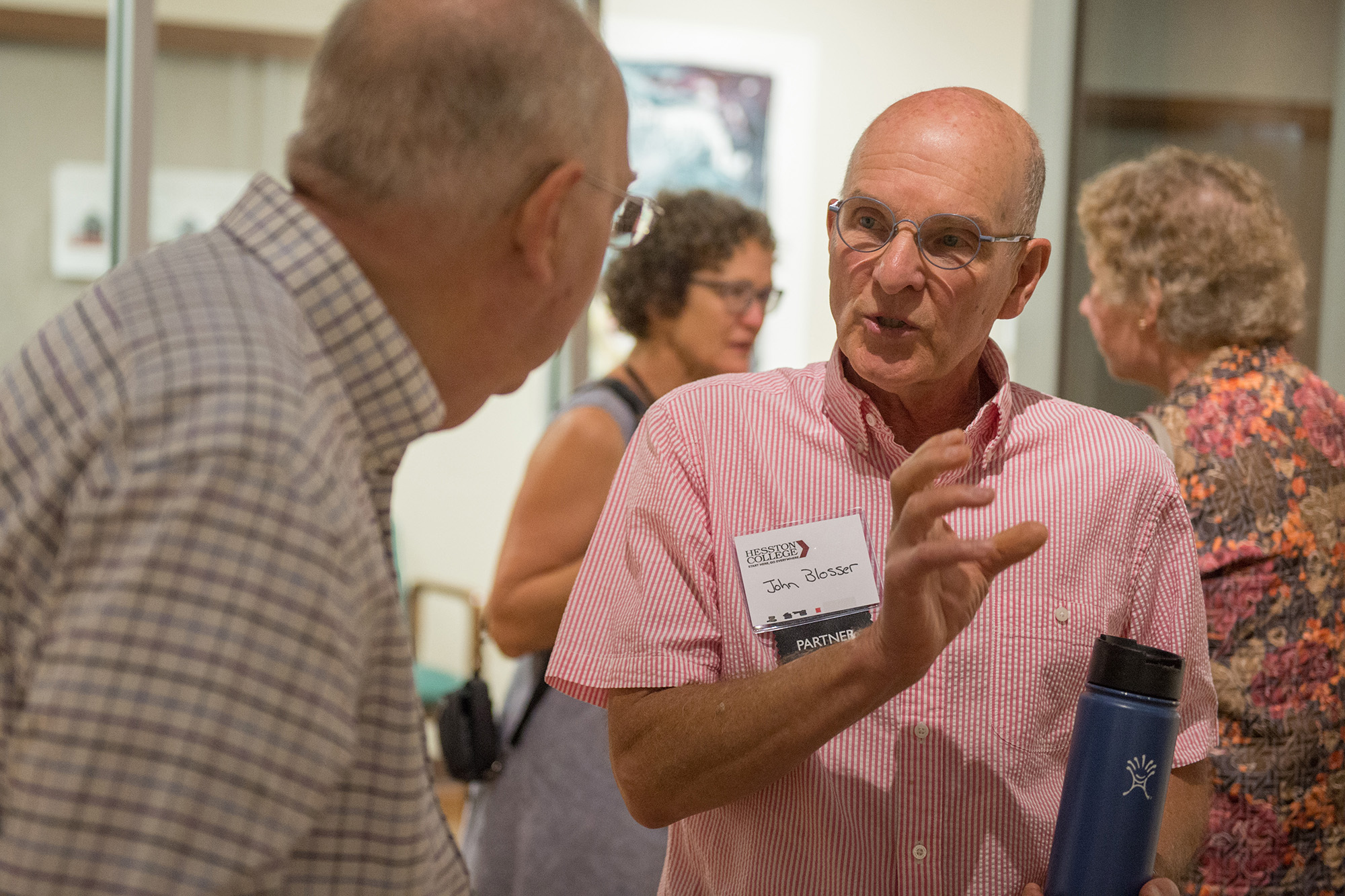 Former art prof John Blosser visits with former physics prof Nelson Kilmer at an artist's reception for Blosser's exhibit.