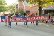 Students represent Hesston College in the community-wide Home Sweet Hesston Homecoming parade. Carrying the banner from left are Romina Xhari ’21 (Lezhe, Albania), Unique Froese ’20 (Ordway, Colo.), Olivia Hernandez ’23 (Hesston) and Sidorella Mjeshtri ’21 (Lac, Albania). Second row carrying flags from left: Brooke Brenneman ’20 (Parnell, Iowa), Josh Wilson ’21 (Canterbury, New Zealand), Kate-Lyn Tivert ’21 (Kigali, Rwanda) and Evelyn Worku ’20 (Addis Ababa, Ethiopia).