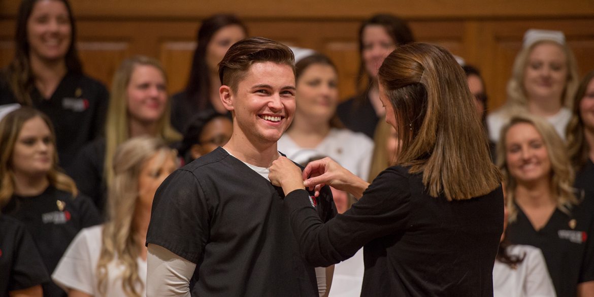 A 2018 graduate receives his nursing pin.
