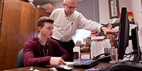 Cal Hartley, a student intern, works with Hesston College Business Manager Karl Brubaker.