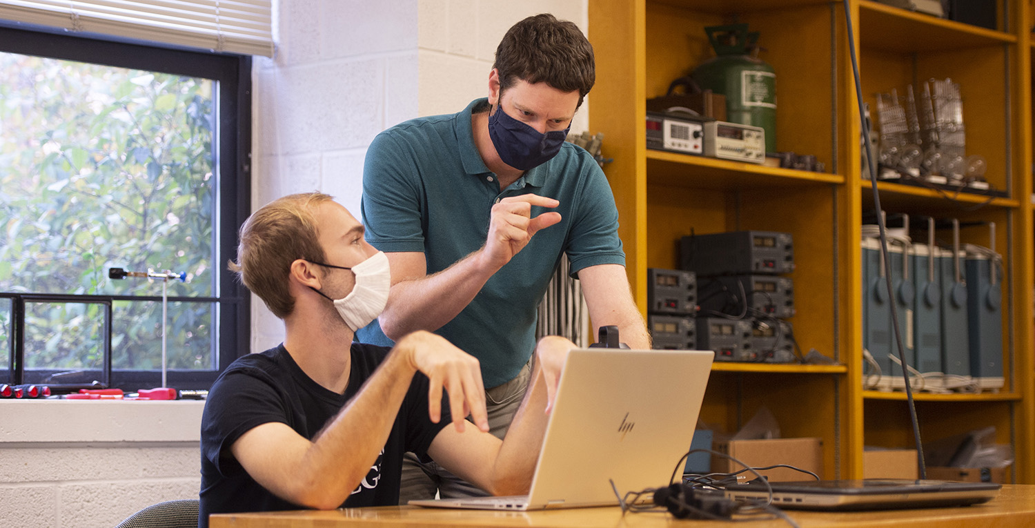 Engineering prof Joel Krehbiel works with sophomore Sam Otto in physics lab.
