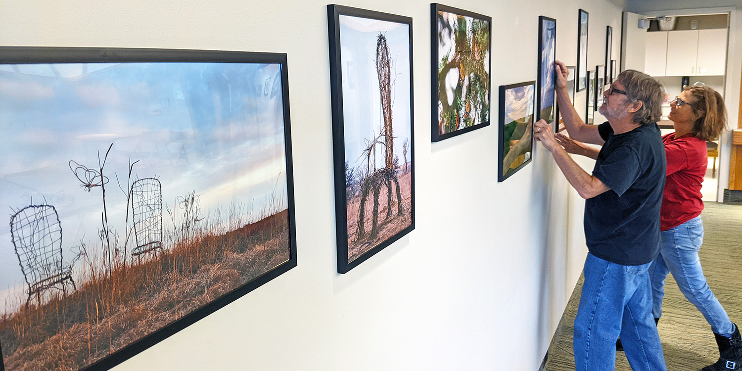 Chip Parker and Ann Zerger hang photos of their works in the Visitor Center.