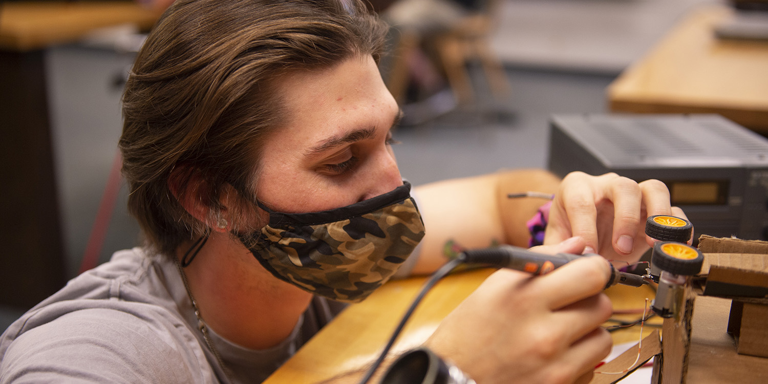 student soldering in physics and engineering lab