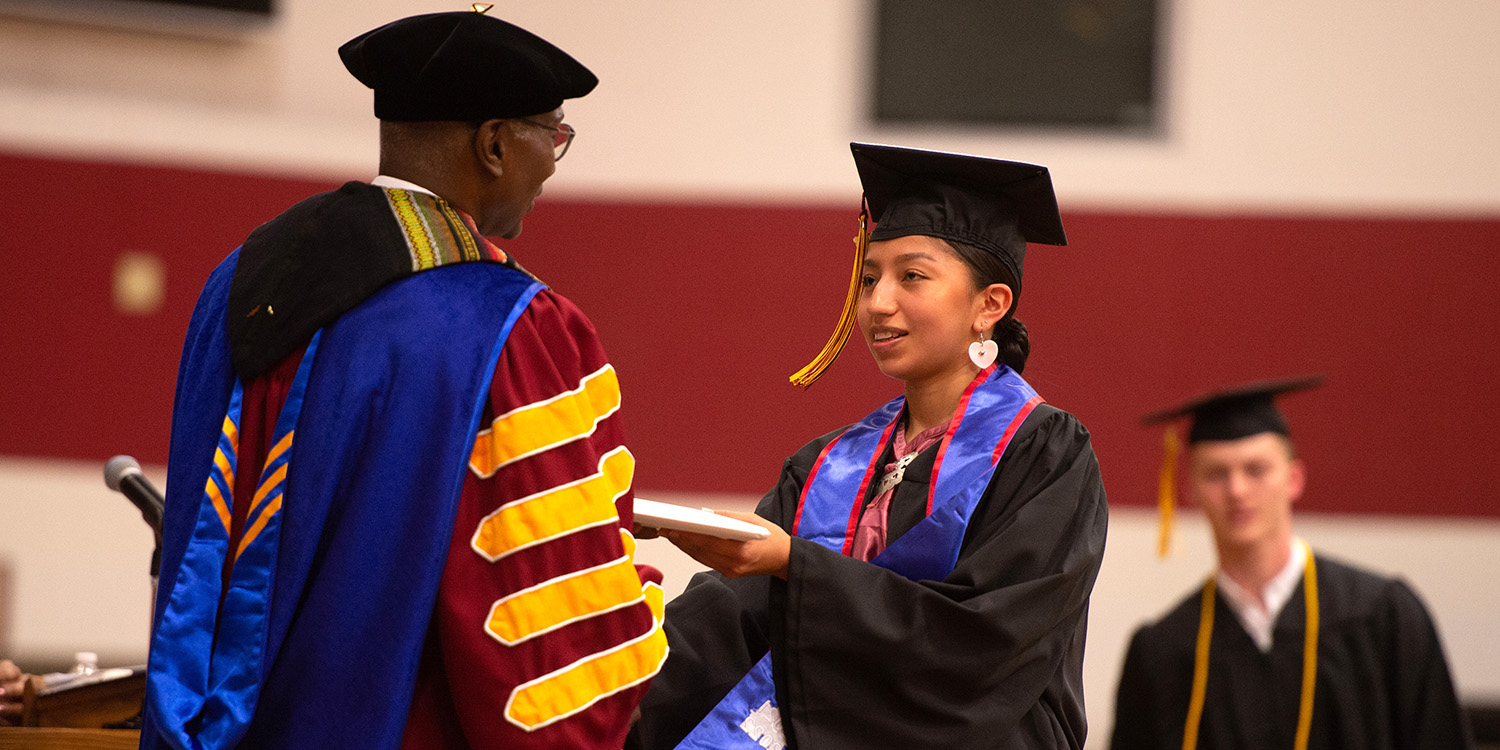 2022 graduate Star Her Many Horses receives her diploma from President Manickam.