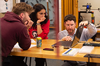 Physics prof Joel Krehbiel works with students in lab.