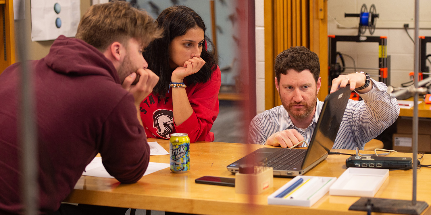 Engineering prof Joel Krehbiel works with students in physics lab.