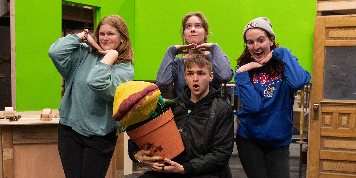 Promotional photo for Hesston College production of Little Shop of Horrors - Rehearsal photo: Cast members Daniel Miller (seated), Caroline Miller, Hadassa Friesen and Meg Beyer rehearsing a scene on the set of Little Shop of Horrors.