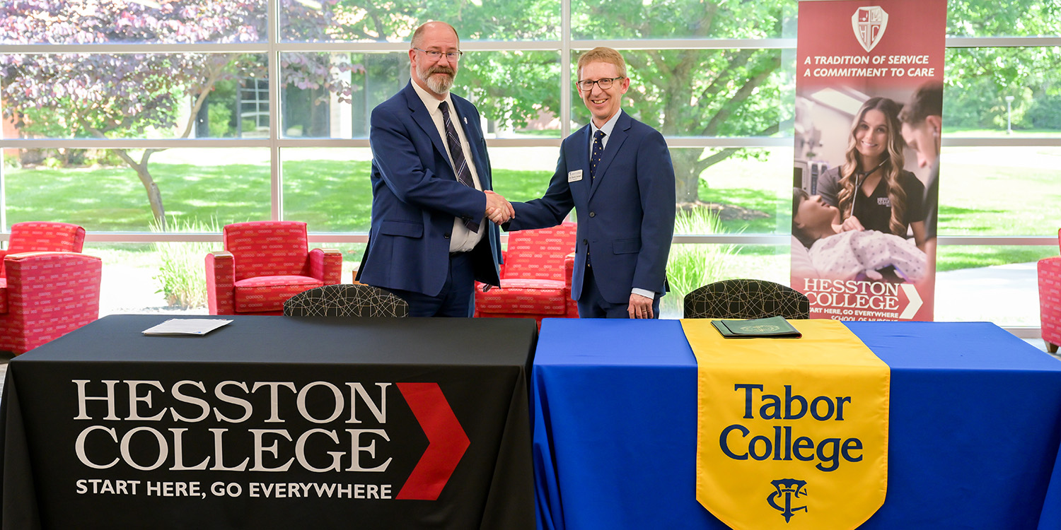 photo - Hesston College Interim President Ross Peterson-Veatch, Ph.D., and Tabor College President David Janzen, Ph.D., shake hands after signing the memorandum of understanding.