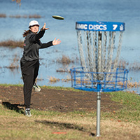 Josalyn completing a disc golf putt