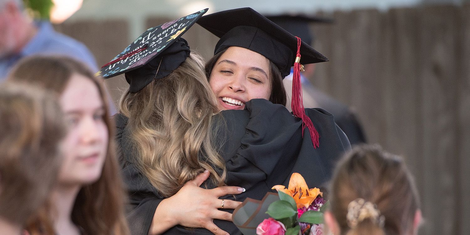 Two graduates hugging at Hesston College commencement 2024
