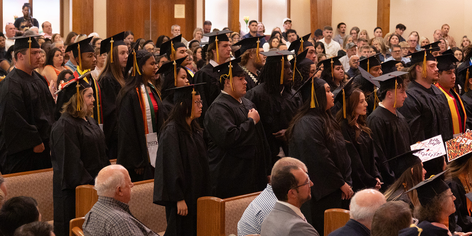 photo of graduate candidates standing at commencement